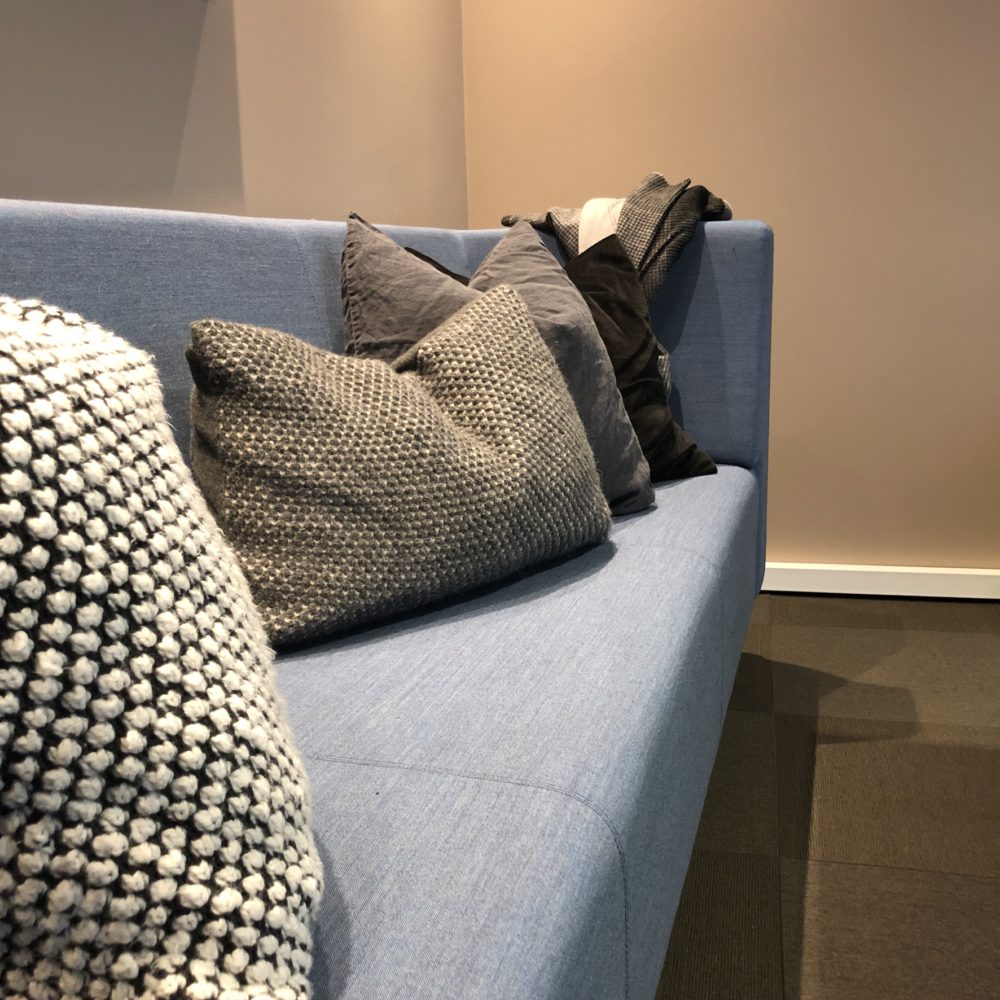 Tøffe pynteputer i hvit og svart som dekor i lysblå sofa på kontoret hos Boli Eiendomsmegler på Steinkjer.