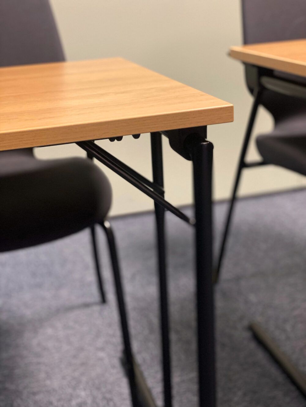 Detaljbilde av møteromsbord med sorte detaljer og naturlig tre benkeplate