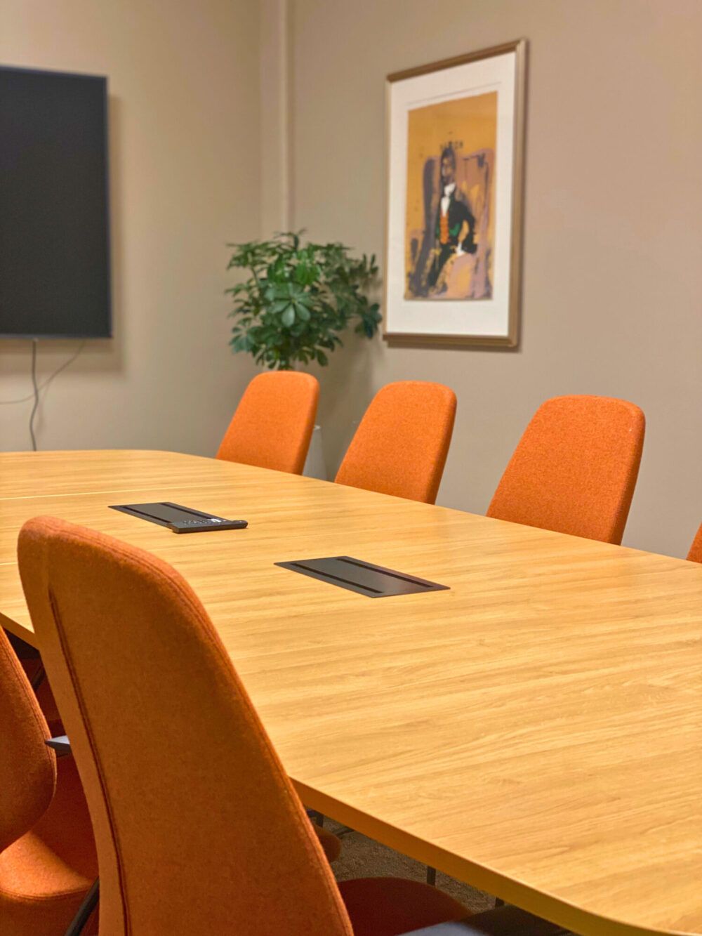 Møterom på Aker Solution. Jordfarger med oransje møteromsstoler fra Kinnarps med bord med svart understell og tre bordplate. Grønne planter er en fin kontrast mot jordfargene